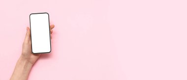 Pembe arka planda cep telefonu olan bir kadın.