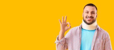 Boynunda atel olan mutlu genç adam sarı arka planda mesaj için yeri olan iyi bir jest gösteriyor.