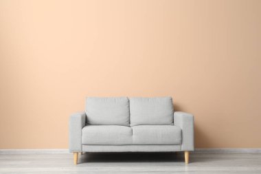Bej duvarın yanındaki gri kanepe.