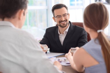 Erkek düğün organizatörü ofiste bir çiftle çalışıyor.