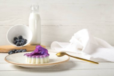 Böğürtlenli panna cotta tabağı ve beyaz ahşap masada güzel ortanca çiçekleri.
