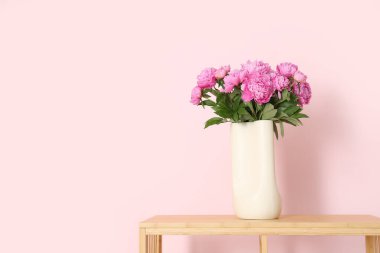 Renk duvarının yanındaki raflarda duran pembe şakayık vazosu.