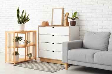 Çekmeceleri, kanepesi ve rafları olan aydınlık oturma odasının içinde.