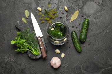 Siyah arka planda korunması için taze salatalıklı kavanoz.