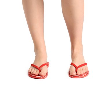 Beyaz arka planda parmak arası terlik giymiş kadın bacakları