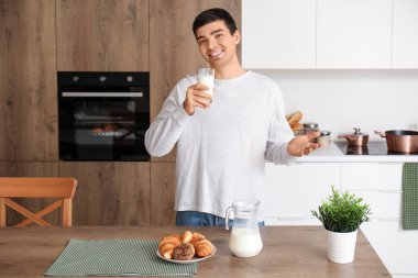 Mutfakta bir bardak sütle genç bir adam.
