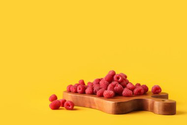 Tahta tahta tahta, sarı arka planda taze ahududu var.