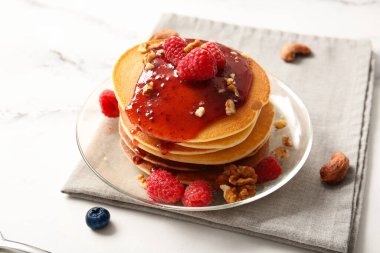 Beyaz mermer arka planda ahududu ve fındıklı lezzetli krepler.