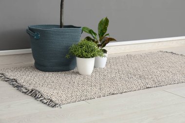 Çiçekler ve gri duvarın yanında şık bir halı.