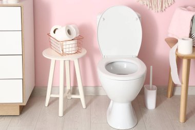 Seramik klozet ve kağıt rulolarla modern tuvaletin şık bir iç mekanı.