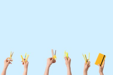 Hands with school supplies on blue background