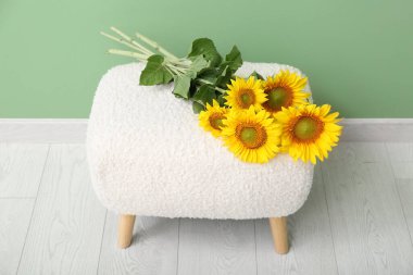 Yeşil duvarın yanında güzel ayçiçekleri olan bankta.