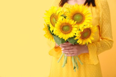 Sarı arka planda güzel ayçiçekleri olan genç kadın, yakın plan.