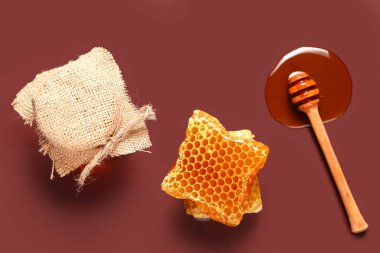 Kırmızı arka planda taraklı ve kepekli bal kavanozu