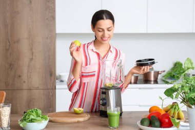 Genç bir kadın evde elma suyu ve blender yapıyor.