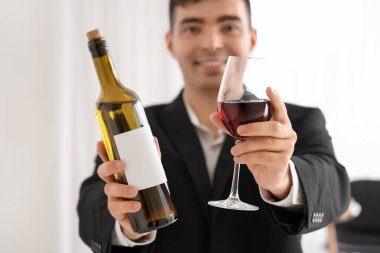 Mutfakta şişe ve bir bardak kırmızı şarapla genç şarap garsonu, yakın plan.
