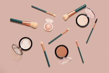 Pembe arka planda makyaj fırçaları ve farklı dekoratif kozmetikler