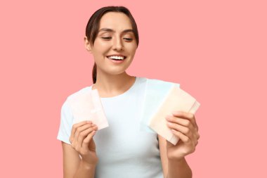 Pembe arka planda regl pedleri olan güzel bir genç kadın.