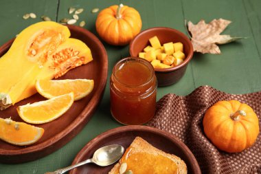 Yeşil ahşap arka planda turuncu balkabağı reçeli kavanozu