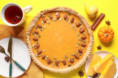 Bademli balkabaklı tart ve sarı arka planda bir fincan sıcak çay.