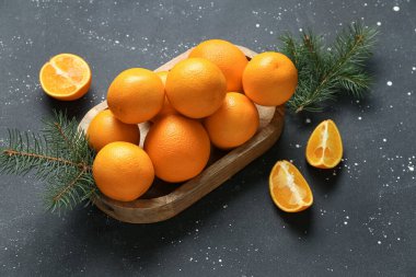 Lezzetli portakallı ahşap tahta ve siyah arka planda köknar dalları