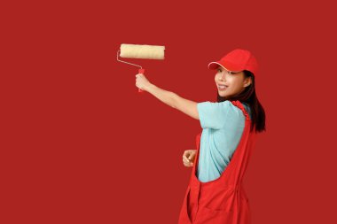 Kırmızı arka planda yuvarlanan Asyalı kadın ressam