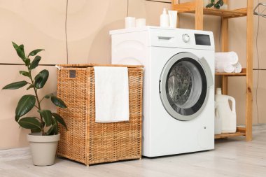 Çamaşır sepeti, çamaşır makinesi ve raf ünitesi olan odanın içi.