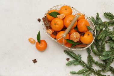 Basket of sweet mandarins with cinnamon, star anise and fir branches on white background