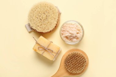 Açık sarı arka planda sabun ve fırçalarla fırçala. Vücut masajı konsepti