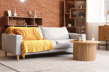 Gri kanepesi, masası ve raf ünitesi olan rahat bir oturma odası.