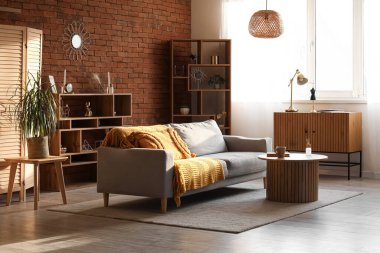 Gün batımında gri kanepesi, masası ve raf ünitesi olan rahat bir oturma odası.