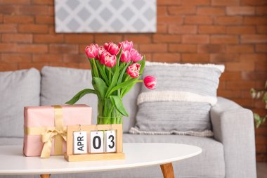 Çiçekli vazo, hediye kutusu ve takvim oturma odasındaki sehpanın üzerinde.