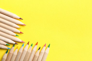 Sarı arkaplanda farklı kalemler, yakın plan
