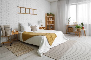 Büyük, rahat bir yatağı ve beyaz tuğla duvarlı merdiveni olan bir yatak odası.