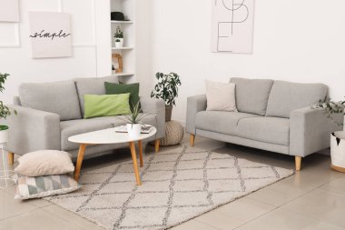 Modern oturma odasındaki gri kanepe, çiçekler, resimler ve kahve masası.