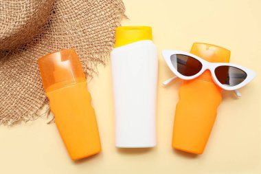 Bej arka planda güneş kremi ve güneş gözlüğü şişeleri