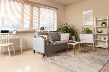 Kanepesi, çiçekleri, raf ünitesi ve sehpaları olan şık bir oturma odası.