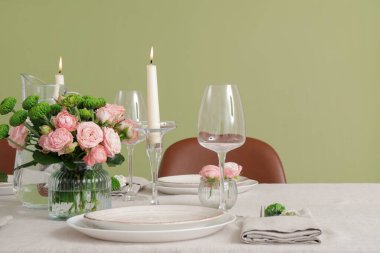 Düğün kutlaması için servis edilen masa, yemek odasındaki yeşil duvarın yanında mumlar ve çiçeklerle dolu.