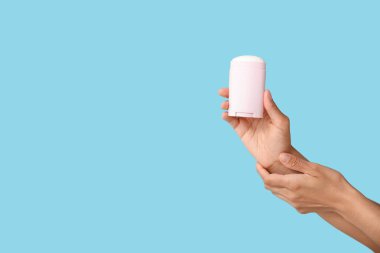 Mavi arka planda deodorantı olan kadın elleri