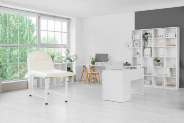 Kanepesi, masası ve raf ünitesi olan endokrinoloji ofisinin içi.