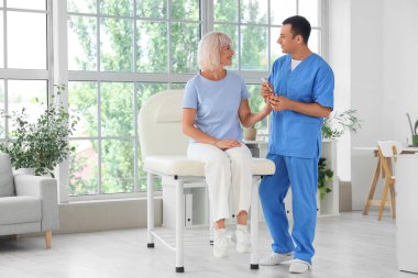 Erkek endokrinolojist elinde tükenmez kalemle klinikte yetişkin bir kadının kan şekerini ölçüyor.