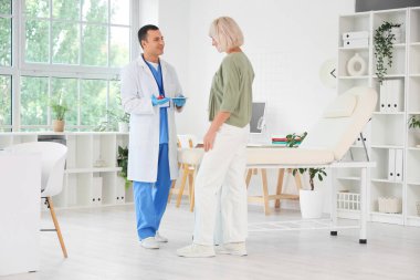 Tiroit bezi modeli olan bir erkek endokrinolog klinikteki olgun kadınlara ilaç yazıyor.