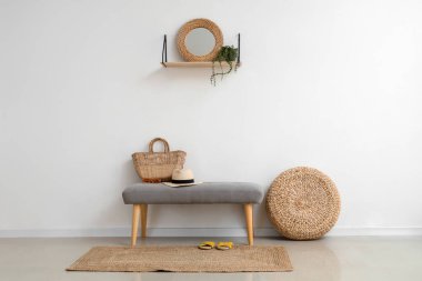 Salondaki ışık duvarının yanında yaz aksesuarları olan yumuşak bir bank.