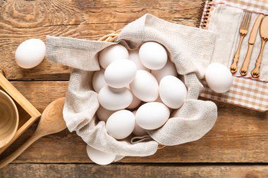 Ahşap arka planda çiğ tavuk yumurtası olan hasır kase.