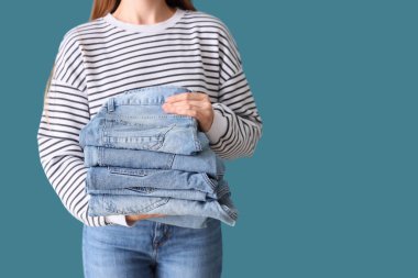 Mavi arka planda şık kot pantolonları olan genç kadın, yakın plan.