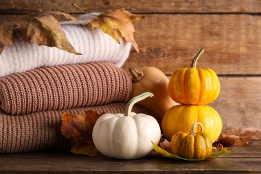 Taze balkabakları örülmüş süveterler ve ahşap arka planda sonbahar yaprakları