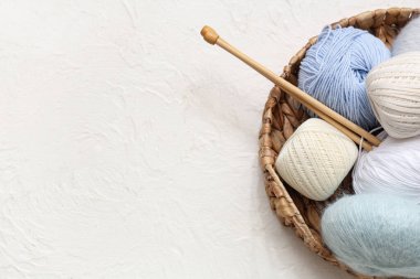 Renkli örgü iplikleri ve beyaz arka planda iğnelerle dolu bir sepet.