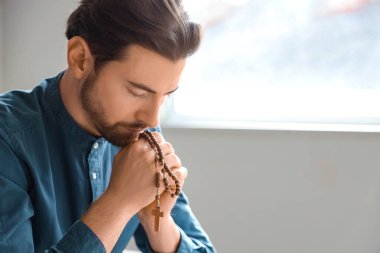 Tespihli bir adam evde dua ediyor.