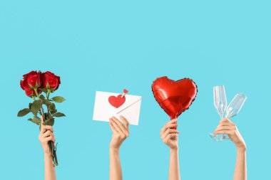 Zarf tutan kadın eller, kalp şeklinde balon, mavi arka planda gözlük ve bir buket kırmızı gül. Sevgililer Günü kutlaması