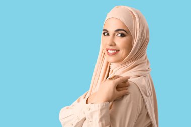 Mavi arka planda bej tesettürlü güzel Müslüman kadın, yakın plan.